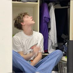 a young man sitting on the floor in front of a closet with his eyes closed