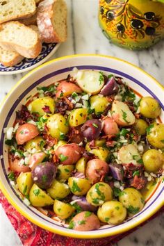 a bowl filled with potatoes and onions on top of a table next to some bread