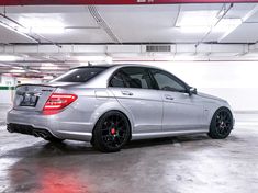 a silver car parked in a parking garage with red lights on the ceiling and black rims