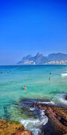 people are swimming in the ocean with mountains in the background