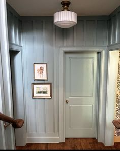 an empty hallway with blue walls and wood flooring is seen in this image from the front door