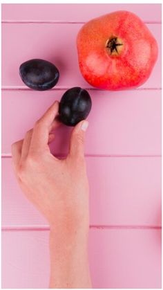 a hand is holding an apple and two black stones on a pink background with the words, how to make chocolate covered apples