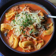 a blue bowl filled with pasta and meat in tomato sauce, topped with parmesan cheese