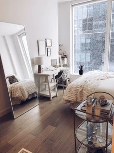 a bedroom with a large mirror on the wall next to a bed and desk in front of a window