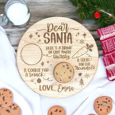 a personalized wooden plate with cookies and milk next to some christmas decorations on a table