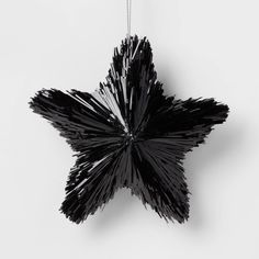 a black star hanging from a chain on a white wall