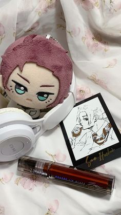 a stuffed doll with headphones and other items laying on a bed next to it