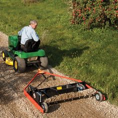 a man riding on the back of a green lawn mower