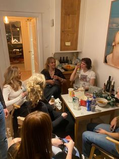 a group of people sitting around a table with drinks and wine bottles on the table