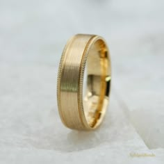 a gold wedding ring on top of a white surface