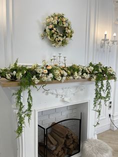 a fireplace decorated with flowers and greenery next to a wreath on the mantel