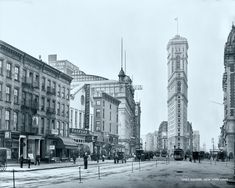 an old black and white photo of people walking down the street in front of tall buildings