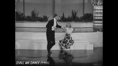 an old black and white photo of a man dancing with a woman in a dress