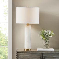 a white lamp sitting on top of a table next to a vase with flowers