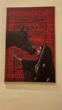 a woman standing next to a brown horse on top of a red and black rug