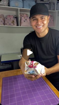 a man sitting at a table holding a wrapped present in front of him and smiling