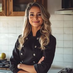 a woman standing in a kitchen with her arms crossed