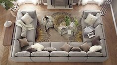 an overhead view of a living room with grey couches and white pillows on the floor