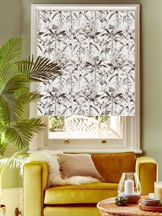 a living room with yellow couches and a window covered in roman blind coverings