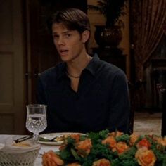 a man sitting at a table in front of a plate with broccoli and carrots on it