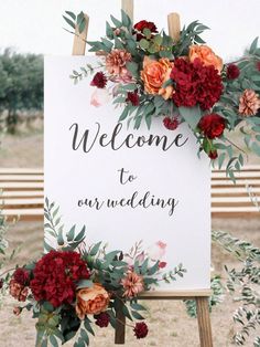 a welcome sign with flowers and greenery on it