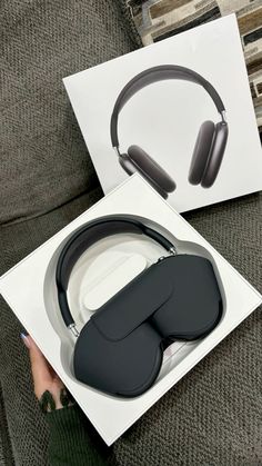 an open box with headphones in it sitting on a couch next to a woman's hand