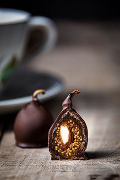 two pieces of chocolate sitting on top of a wooden table next to a cup and saucer