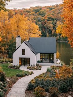 a white house surrounded by trees with fall foliage in the background and a path leading to it