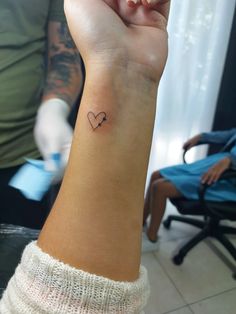 a small heart tattoo on the wrist