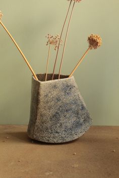 three dried flowers in a concrete vase on a table