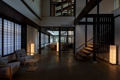 an empty room with several chairs and tables in front of the windows, next to a stair case