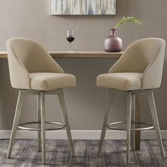 two chairs sitting at a table with a wine glass and vase on the counter top