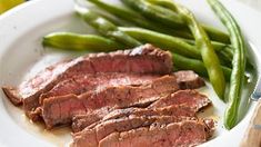 some meat and green beans on a white plate