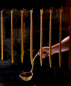 a person is stirring some food in a pan with spoons hanging from the ceiling