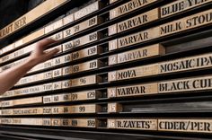 a person reaching out to touch stacks of wooden boxes with names on them in front of a building