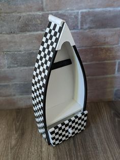 a black and white boat shaped box sitting on top of a wooden table next to a brick wall