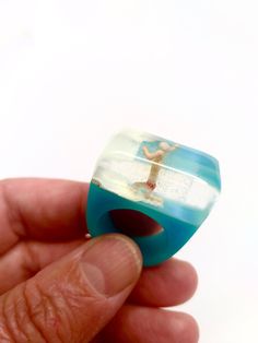 A child playing with the sea in a diorama scene.  This ring is made with a miniature, white and blue resin bedded in a special mold and after polished to be shinny. The ring is a starting conversation!  I can enlarge to a 7 USA size. If you need help for your ring size, check out http://en.wikipedia.org/wiki/Ring_size  My work features brilliant colors and clear resin.The resin results in a durable piece that has a natural shine and is resistant to scratches. I hand sand the edges for a smooth piece with a beautiful luster. I hand make each piece in my studio in Barcelona and no two are alike. This jewelry is handmade and slight imperfections are part of the character of the piece.  I will send the order packed in a recycled craft box, ready to gift! I ship through registered mail with the Ocean-inspired Blue Ring For Gifts, Ocean-inspired Blue Ring For Gift, Ocean-inspired Blue Rings As Gifts, Handmade Blue Resin Rings, Unique Blue Resin Rings, Blue Resin Rings For Gifts, Blue Resin Rings Perfect As Gifts, Blue Resin Rings Perfect For Gifts, Ocean-inspired Blue Resin Jewelry