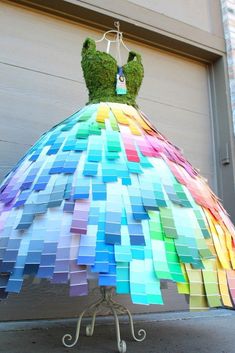 a dress made out of colored paper sitting on top of a metal stand