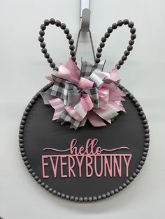 a black and pink sign that says hello bunny with a bow hanging from it's side