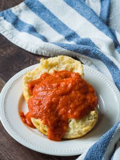 a white plate topped with an egg muffin covered in marinara sauce next to a blue and white towel