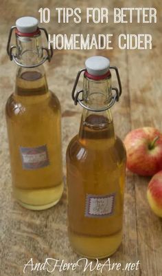 two glass bottles filled with apple cider sitting on top of a wooden table