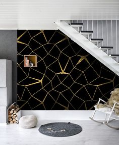 a room with black and gold wallpaper next to a stair case