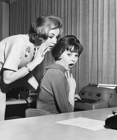 an old photo of two women in front of a computer screen, one on the phone