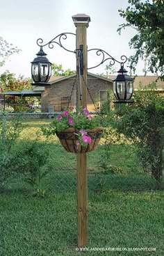 an old fashioned lamp post with flowers hanging from it's sides in the yard