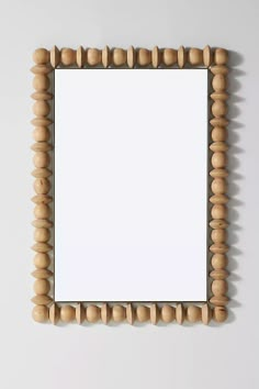 a mirror that is made out of wood beads and has a white paper in the middle