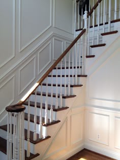 a white staircase with wooden handrails in a house