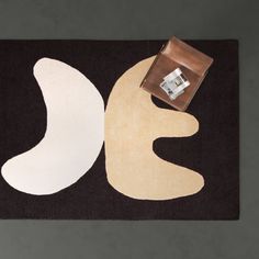 a black rug with two white shapes on it and a brown box next to it