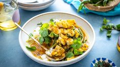 a white bowl filled with food on top of a blue table next to other dishes