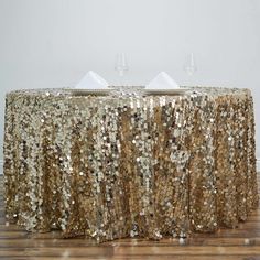 a table covered in gold sequins with two wine glasses on top