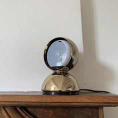 a table with a mirror on top of it next to a white wall and a wooden shelf